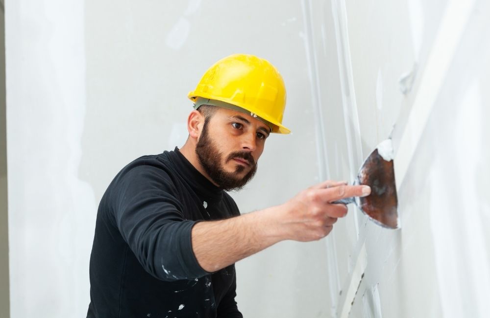 Guy plastering with construction hat