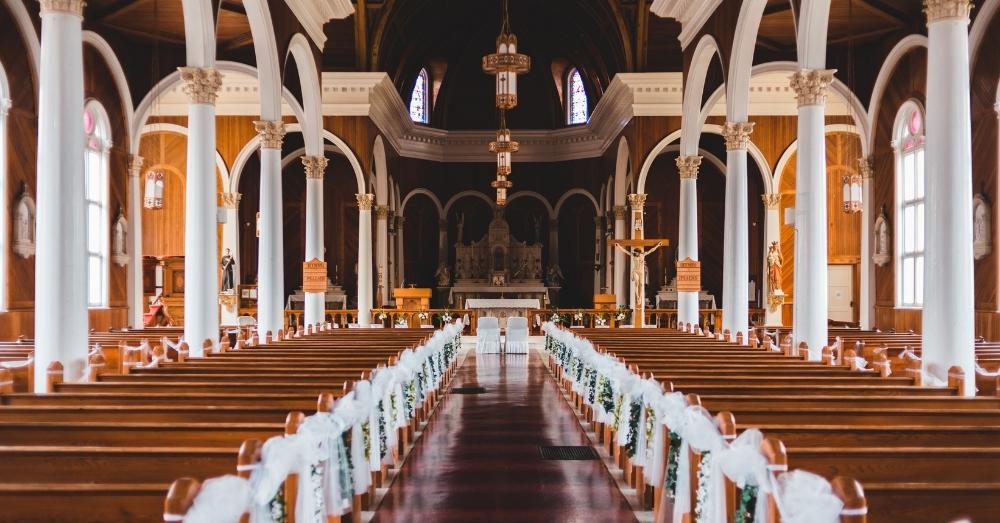 Beautiful church interior with wooden pews, tall columns, and decorated altar.