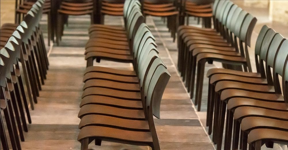 Rows of empty wooden chairs with a curved design.
