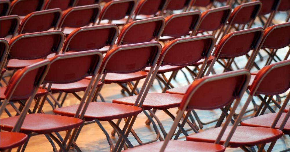 Rows of empty, dark red folding chairs.
