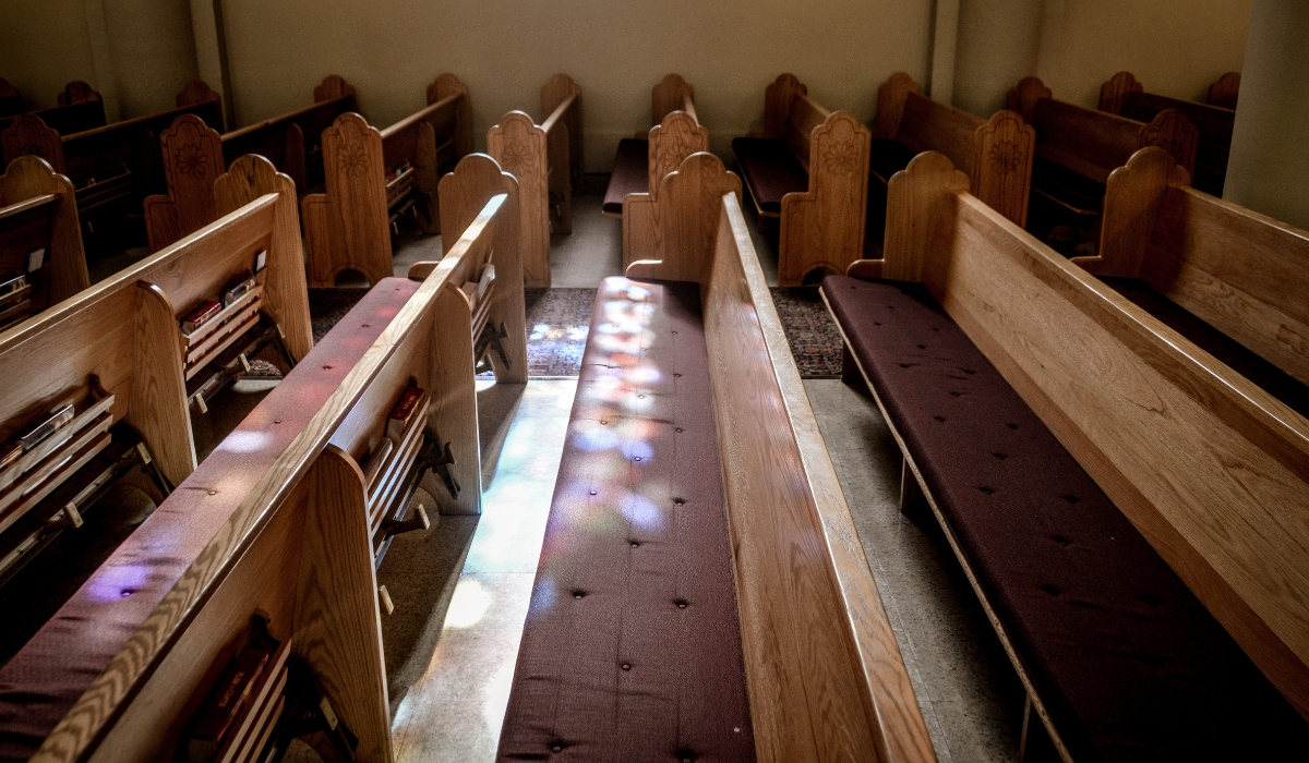 empty wooden church pews with dark cushions