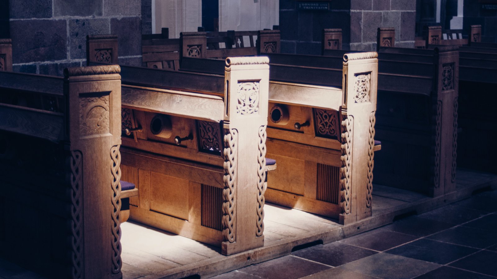 Beautifully carved wooden pews inside a dimly lit church, highlighting architectural elegance and craftsmanship.