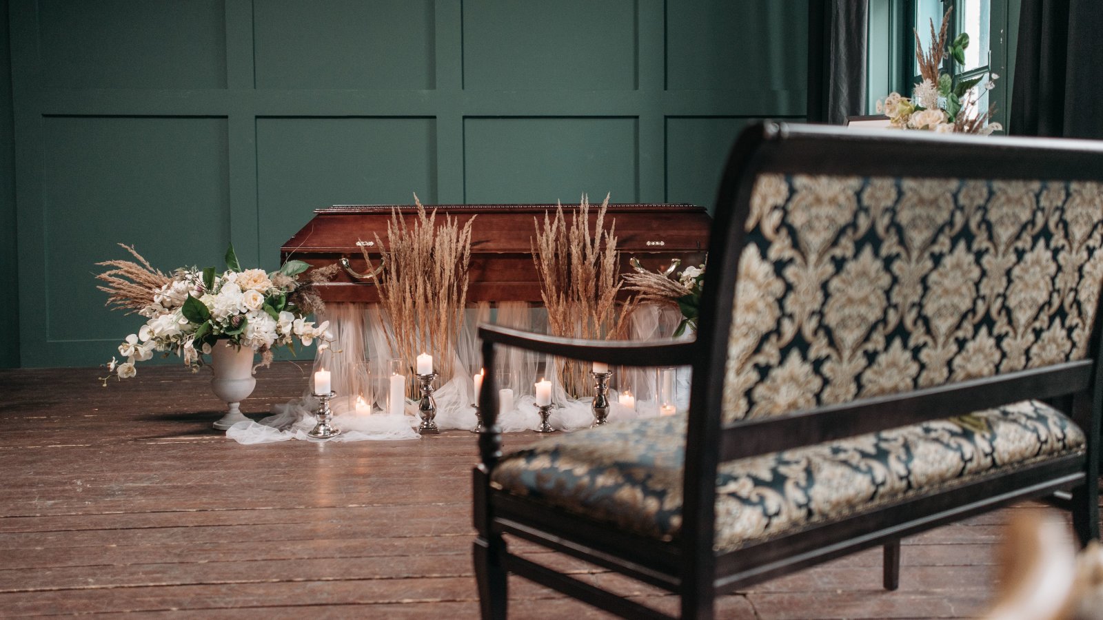 A beautifully decorated funeral room featuring a coffin, flowers, and candles set in a serene atmosphere