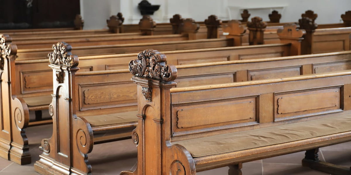 Rows of antique wooden church pews featuring detailed, ornate carvings