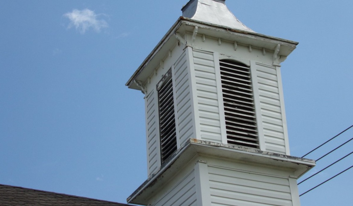 Low angle view of classic white church steeple with cross against clear sky