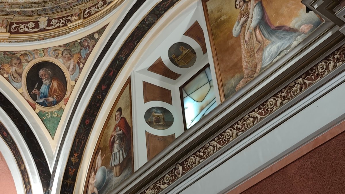 Artistic ceiling paintings in a historic church illustrating intricate historic paint colors and designs.