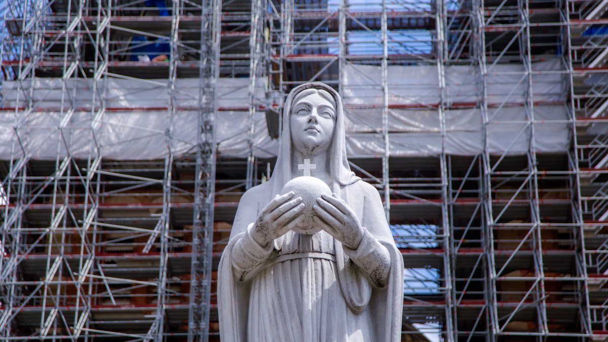 Statue of Virgin Mary amidst scaffolding indicating active preservation or restoration work